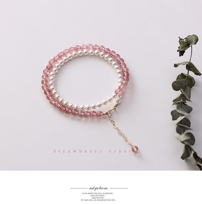 Multistrand bracelet with pink and white beads on a light background with a leaf stem.