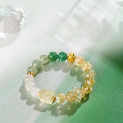Beaded bracelet with green, gold, and clear stones on a light background