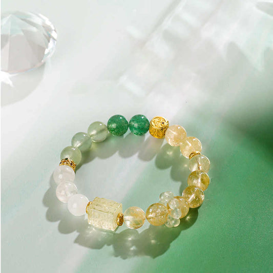 Beaded bracelet with green, gold, and clear stones on a light background