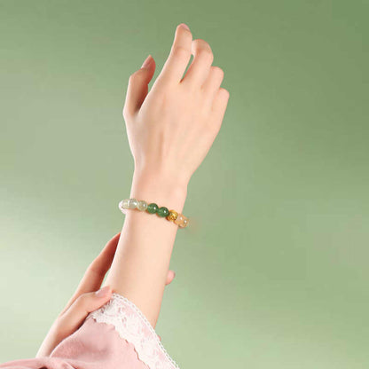 Hand wearing a bracelet with green beads against a light green background