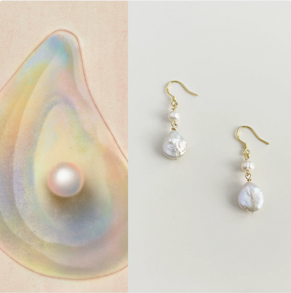 Pearl earring set with a pearl inside a shell on a light background