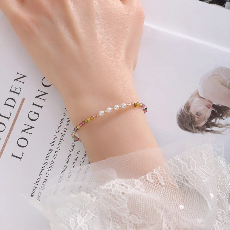 Woman's wrist wearing a colorful beaded bracelet on a newspaper background