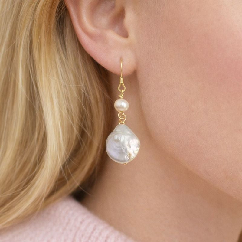 Pearl earrings being worn by a person with blonde hair.