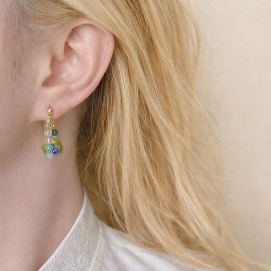 Close-up of a person wearing colorful beaded earrings with blonde hair.