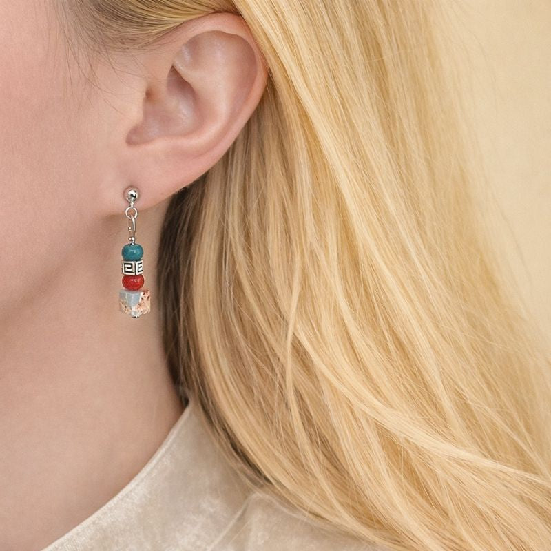 Close-up of a person wearing colorful beaded earrings with blonde hair.