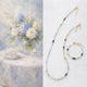 Beaded necklace and bracelet set with a still life painting of flowers and jewelry.