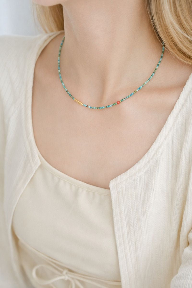 Necklace with small beads worn by a person in a light-colored top