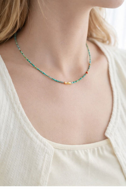 Necklace with small beads worn by a person in a white top