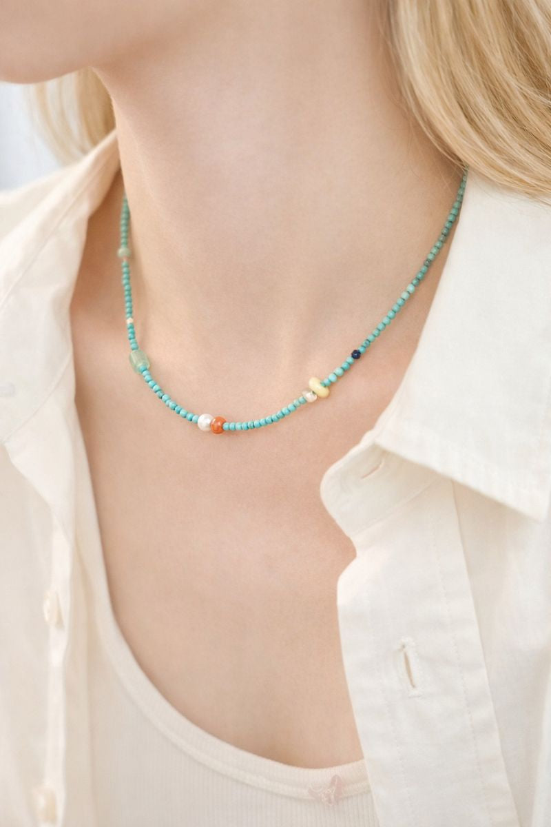 Necklace with colorful beads worn by a person in a light-colored shirt