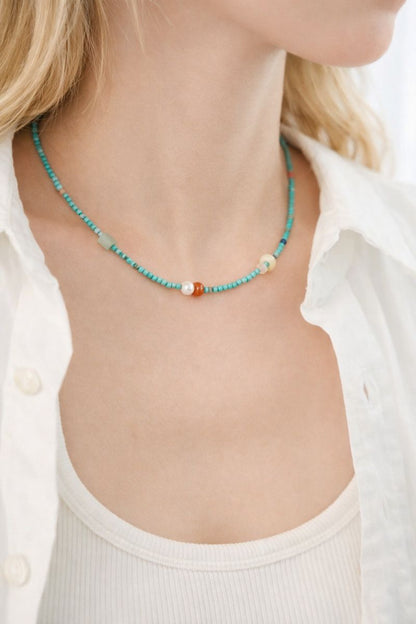 Necklace with turquoise beads and a white shirt worn by a person