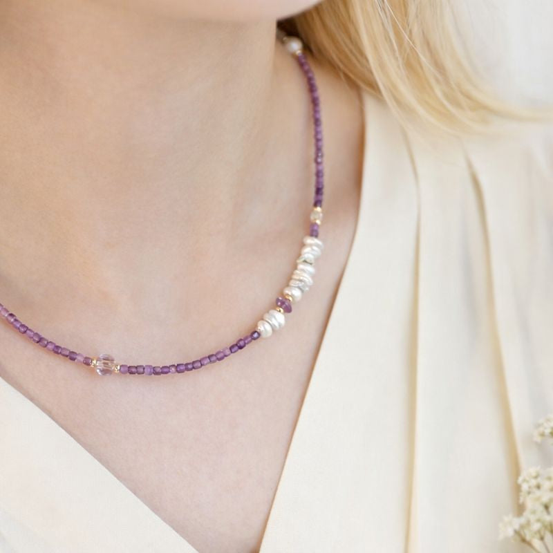 Necklace with purple and white beads worn by a person