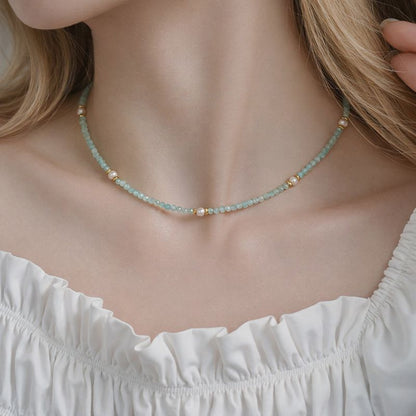 Necklace with small beads worn by a person in a white top