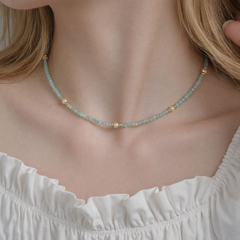 Necklace with small beads worn by a person in a white top