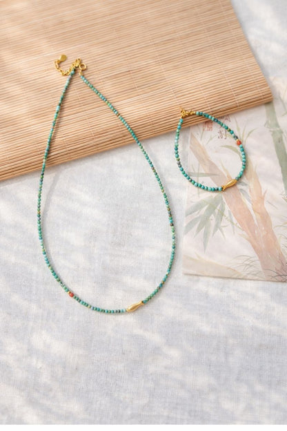 Beaded necklace and bracelet on a textured surface with a magazine underneath